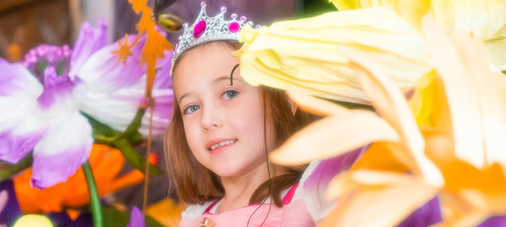 Little girl dressed like a princess between colorful enchanting flowers